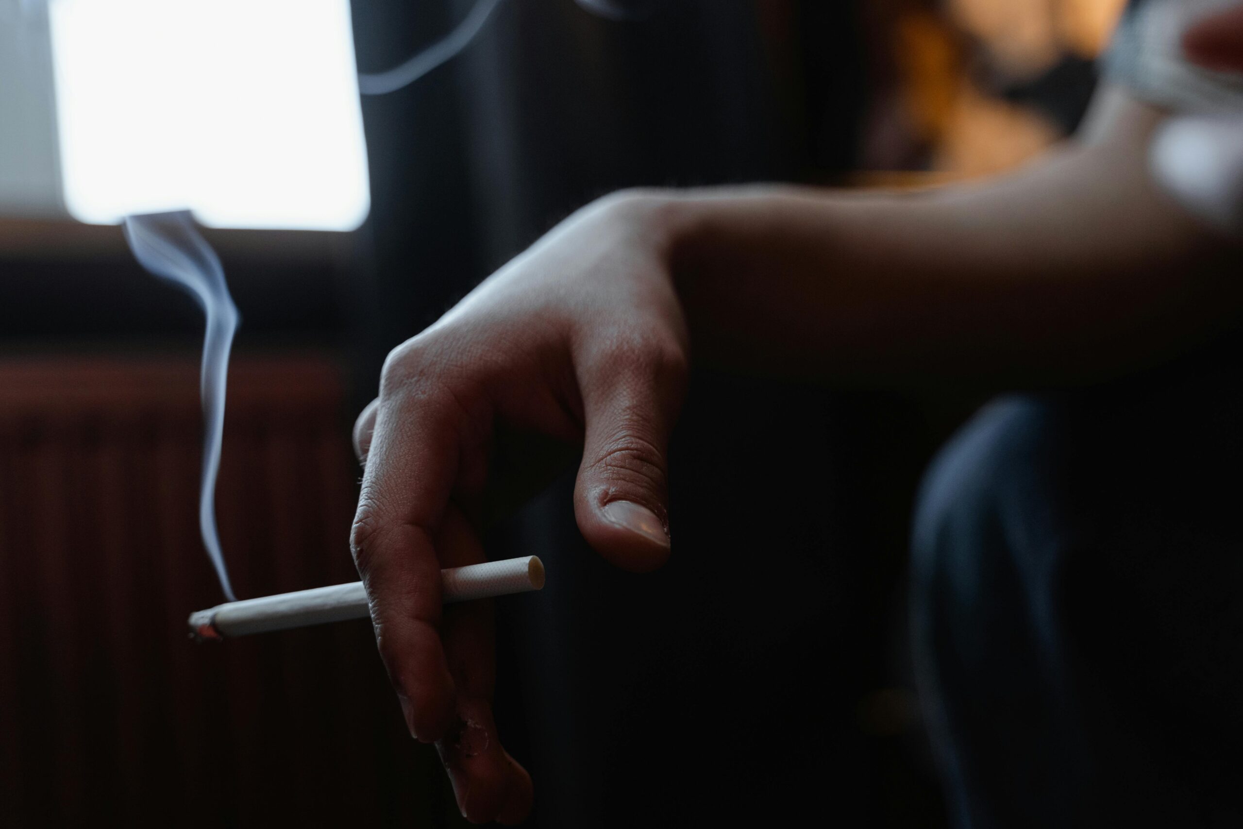 ruka s cigaretou - člověk přemýšlí o léčbě závislosti na nikotinu